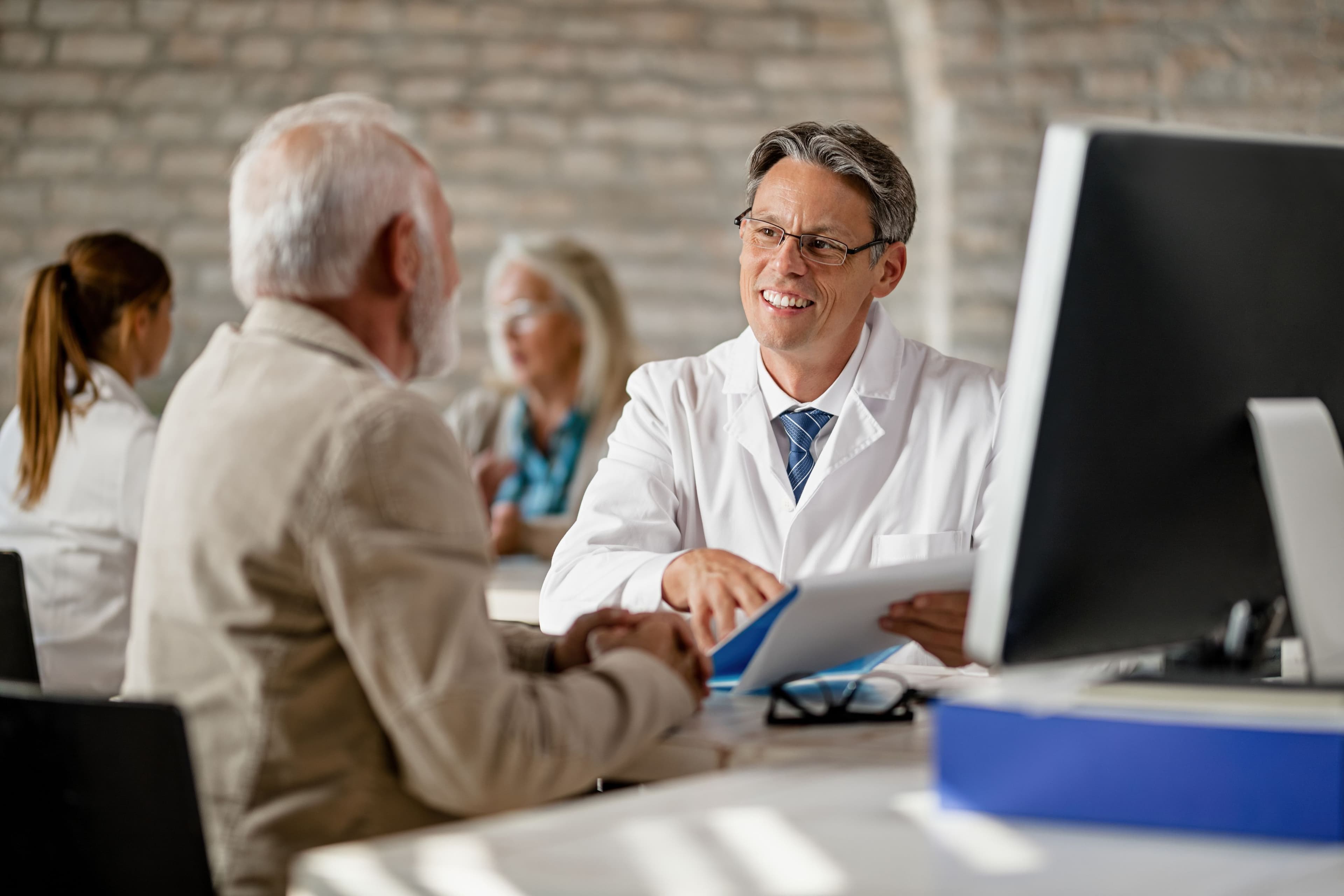 Doctor consulting with an older patient during a personalized healthcare appointment, reviewing treatment options, medical records, and wellness plans