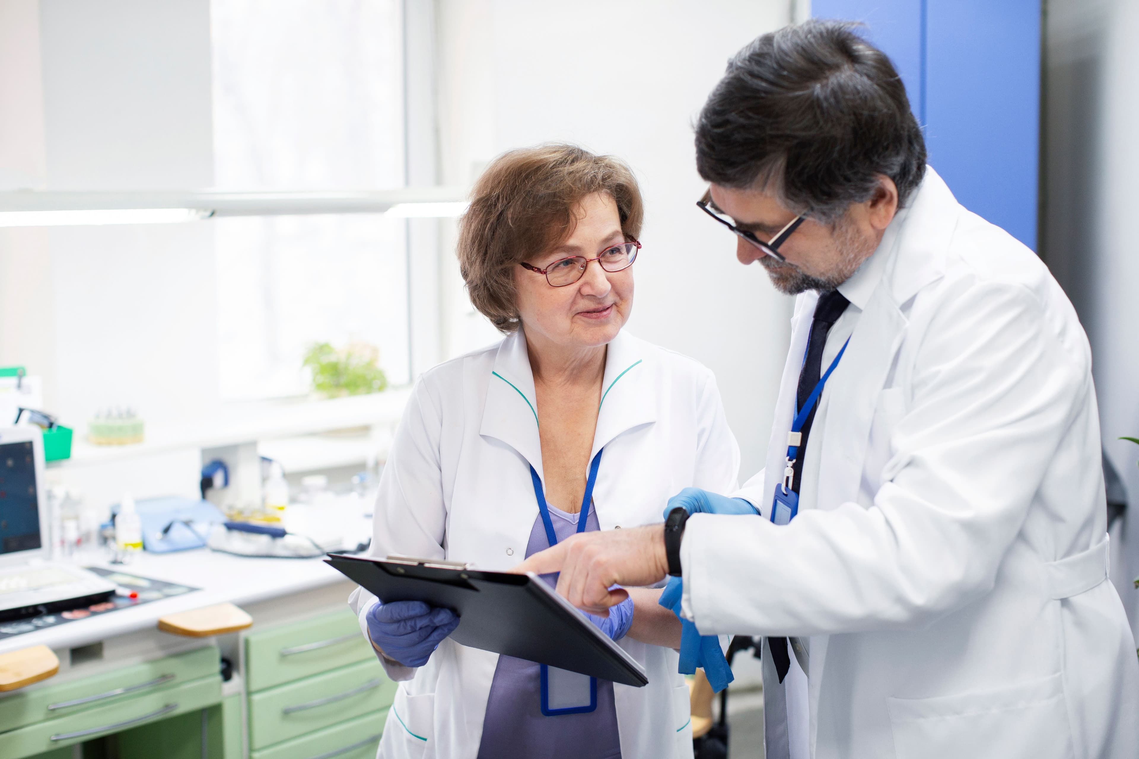 Healthcare professionals reviewing patient information and clinical data on a clipboard in a modern medical facility, supporting collaborative care and evidence-based healthcare